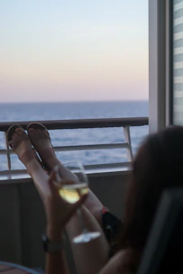 Cozy seaside apartment balcony with sunset view and a glass of wine.