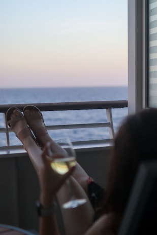 A happy guest relaxing on a balcony overlooking the peaceful beach at sunset.