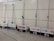 A row of portable signs with telescopic poles, leaning against a tiled wall. Each sign displays information in multiple languages, including arrows and symbols likely related to public transportation routes or stations.