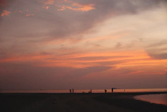 A vibrant group of travelers enjoying a scenic sunset on a beach, symbolizing joyful holiday experiences.