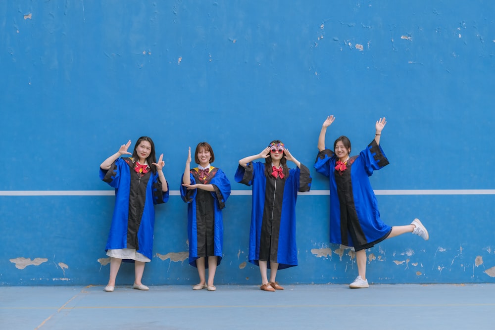 um grupo de meninas em vestidos pretos e brancos na frente de uma parede azul