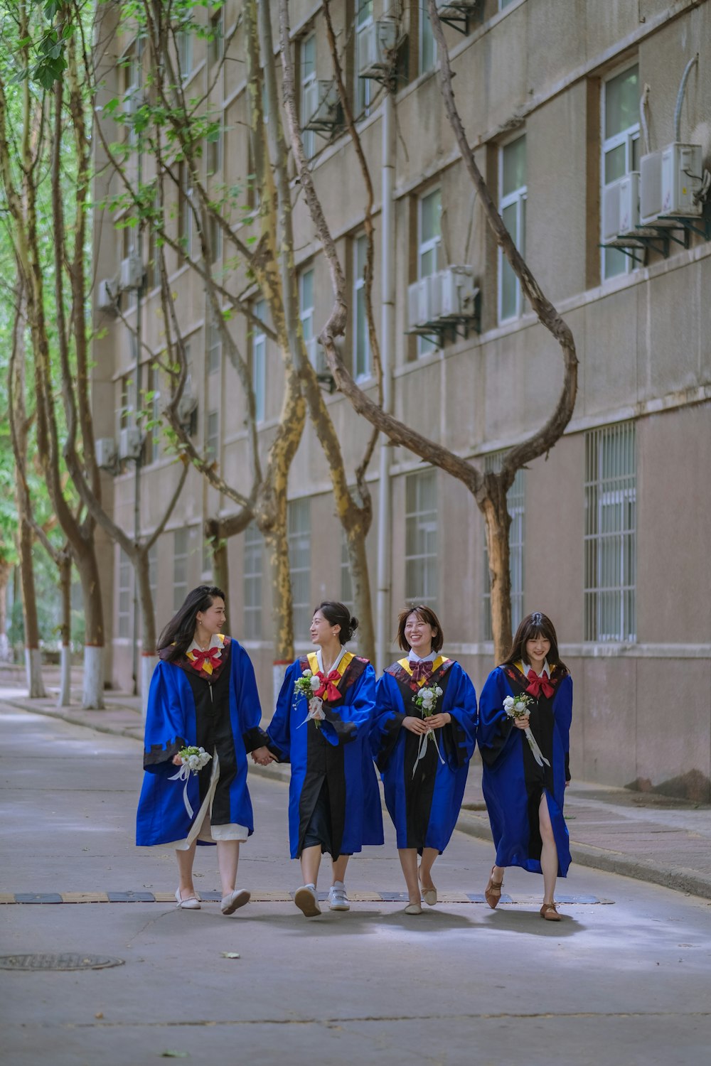 a group of women in blue gowns walking down a street