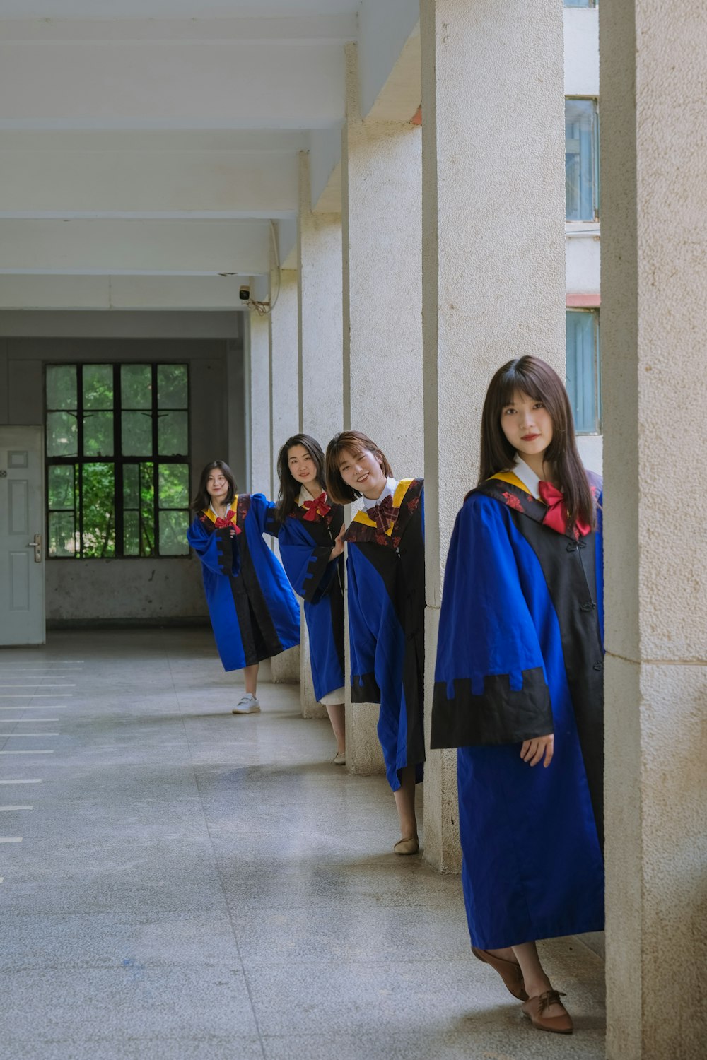 廊下に立つ青いガウンを着た女の子のグループ