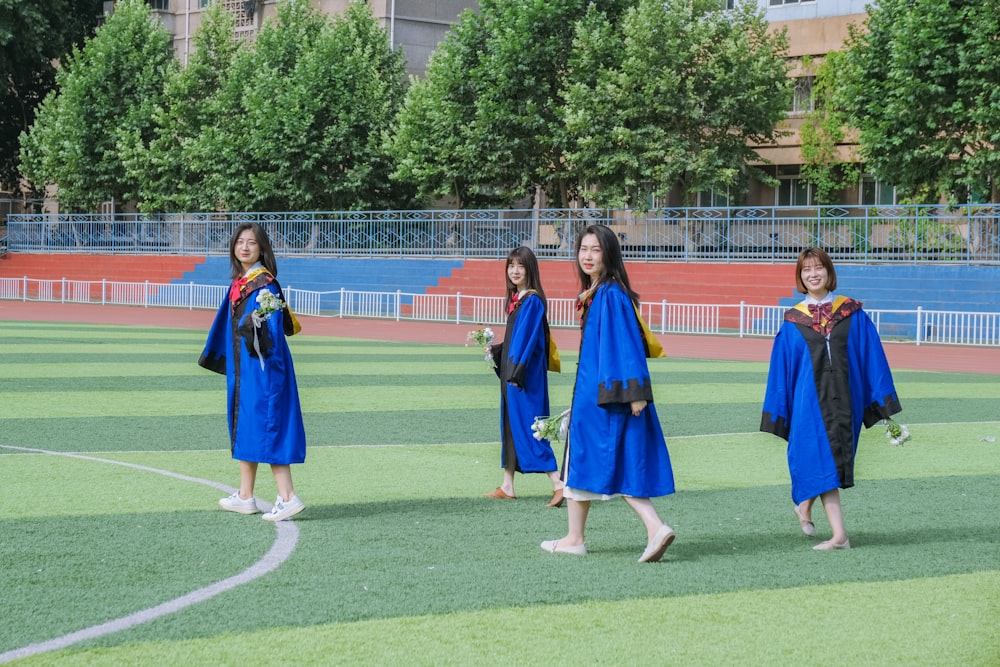 a group of girls in blue gowns on a grass field