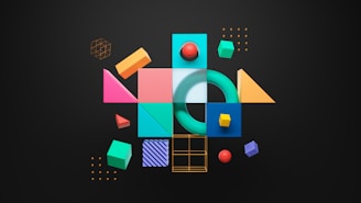 A collection of colorful geometric shapes arranged on a dark background, including cubes, spheres, pyramids, and circles in vibrant colors like cyan, pink, yellow, and red. Each shape has a glossy, three-dimensional appearance and is organized in a playful, abstract configuration.