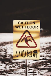 Photo showing a slippery floor hazard sign in a public building.