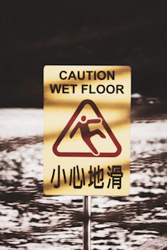 Close-up of a slippery wet floor sign in a busy NYC subway station.