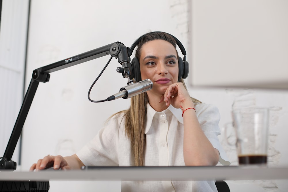 a woman wearing headphones and sitting at a desk with a microphone