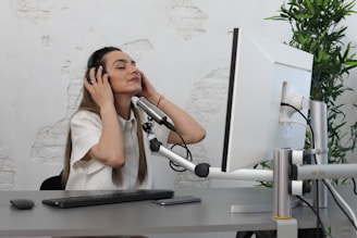 A calm, focused woman using headphones while engaging with a nervous system regulation course on her computer.