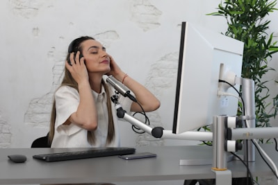 A calm, focused woman using headphones while engaging with a nervous system regulation course on her computer.