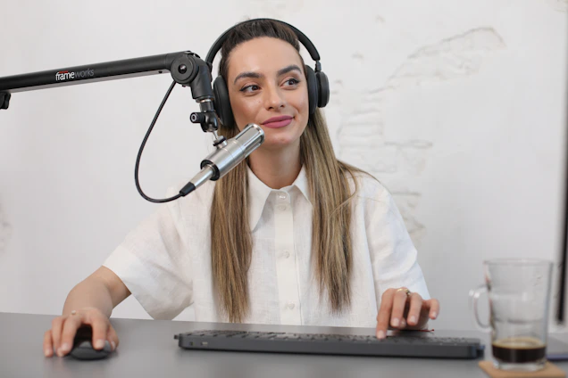 A person sitting at a desk surrounded by paperwork, looking determined while recording a podcast.