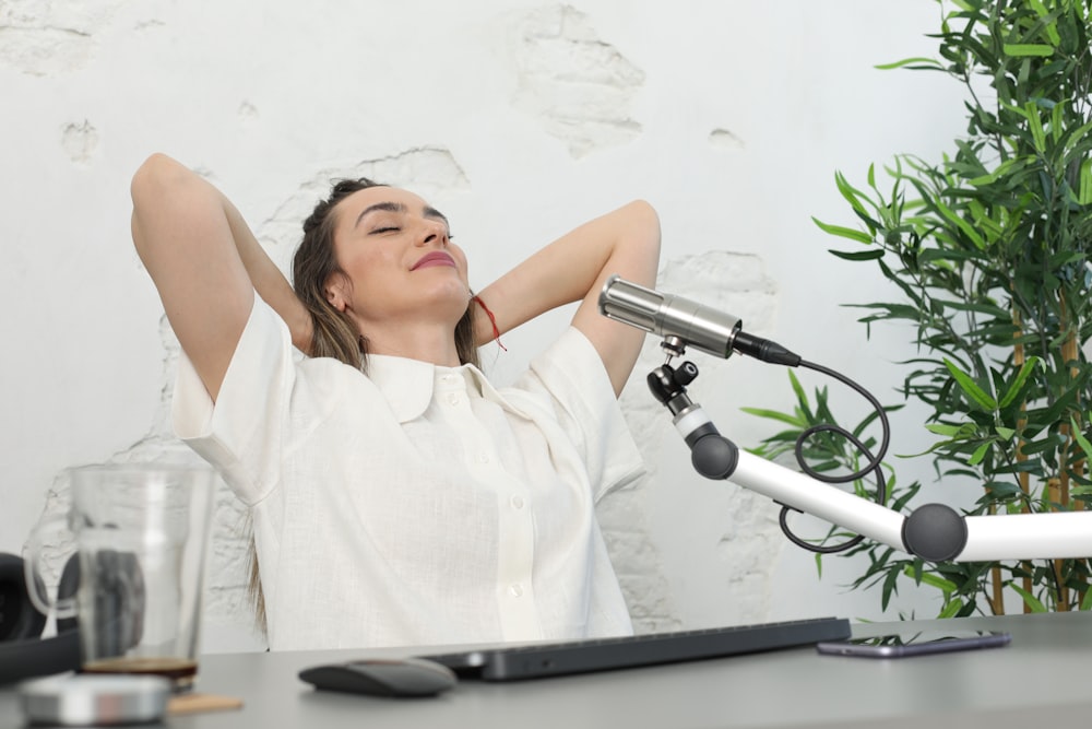 a woman lying on a desk with a microphone and a plant