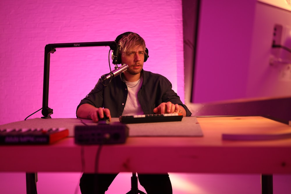 a man wearing headphones and sitting at a desk with a microphone