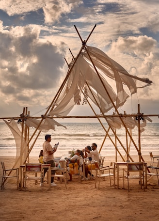 A sturdy metal-frame canopy sheltering a family at a beachside gathering.