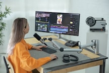 a person sitting at a desk with a computer and a microphone