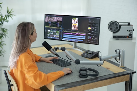 a person sitting at a desk with a computer and a microphone