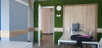 A modern office corner featuring plants and design elements in dry green and blue tones.