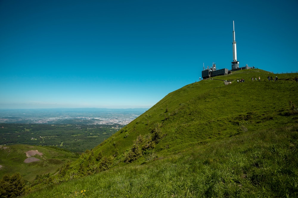 a grassy hill with a building on it and a tower in the distance