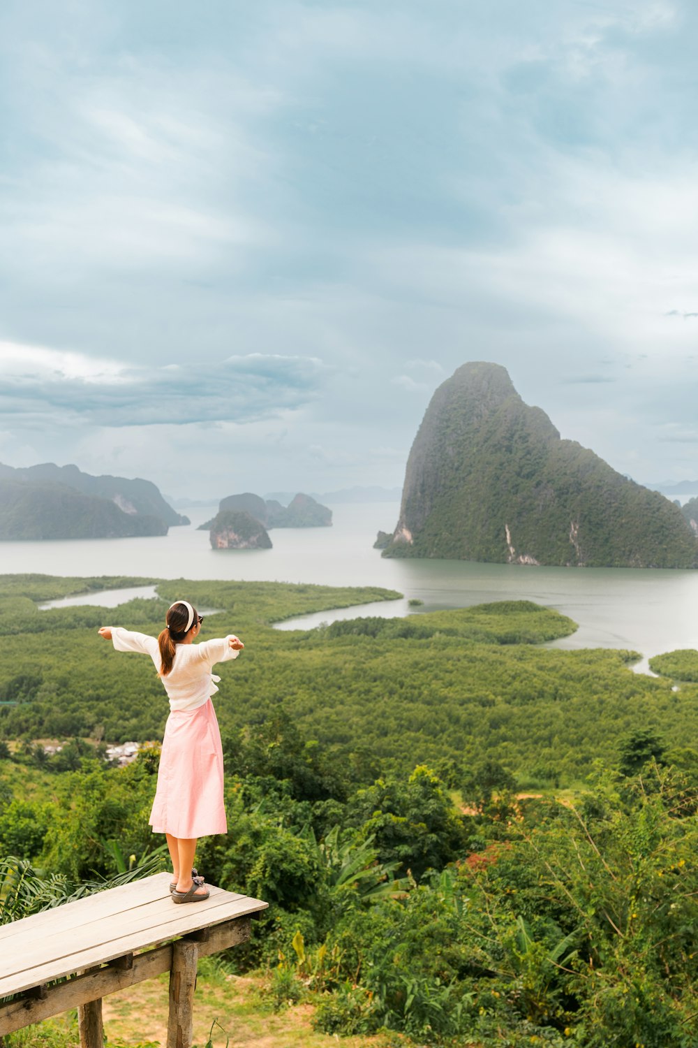 a person standing on a wooden bench overlooking a body of water