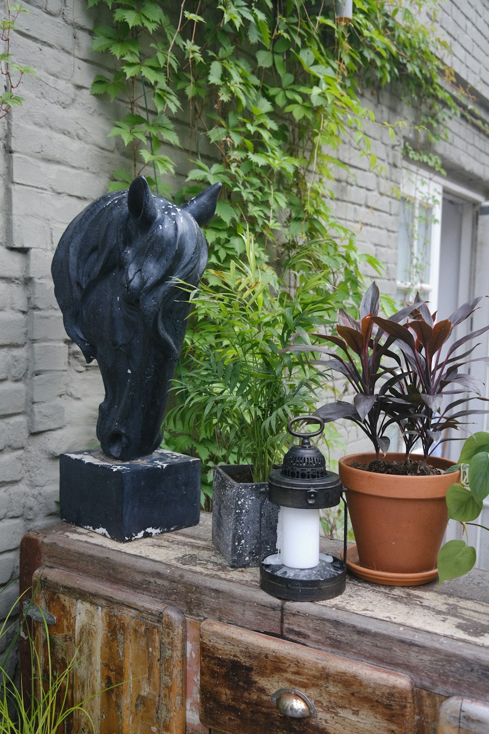 una estatua de un gato junto a una planta y una maceta