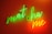Bright neon text spelling 'matcha me' in a cursive style. The words are illuminated in green and orange neon lights against a warm, reddish-brown background.