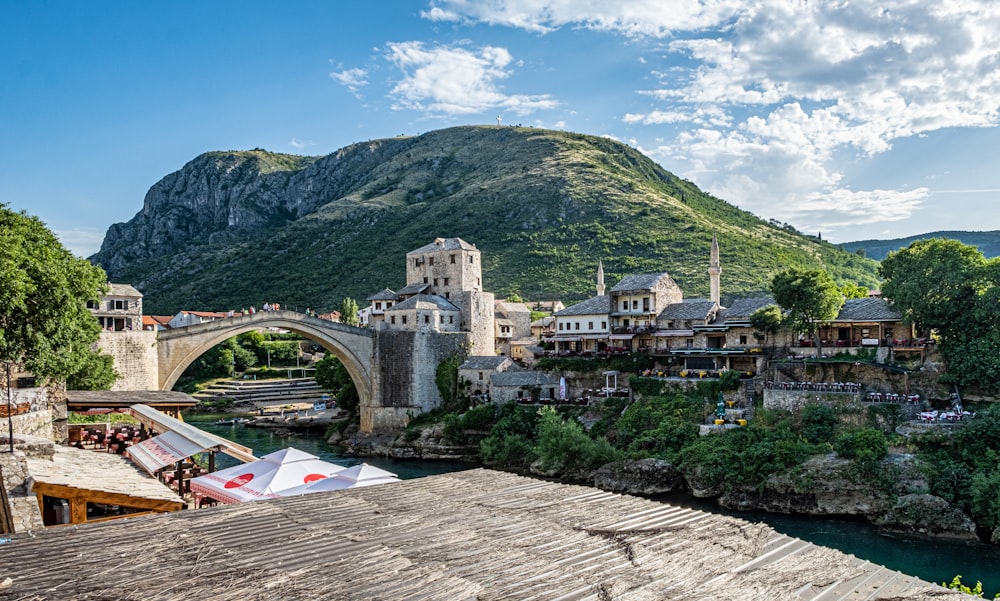 a bridge over a river with buildings and a hill in the background