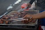A chef grilling meats outdoors at a barbecue event.