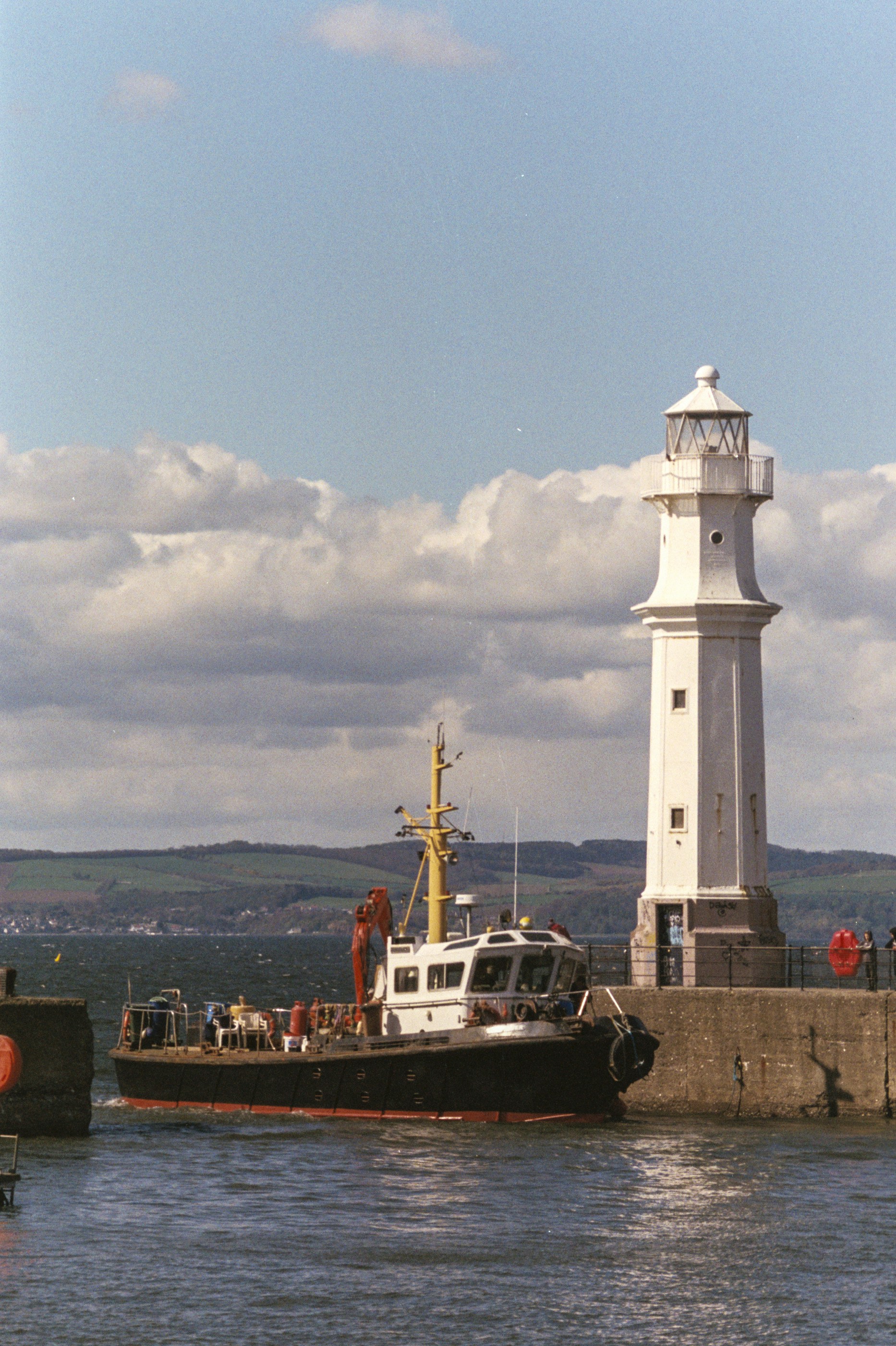 a boat in the water by a lighthouse