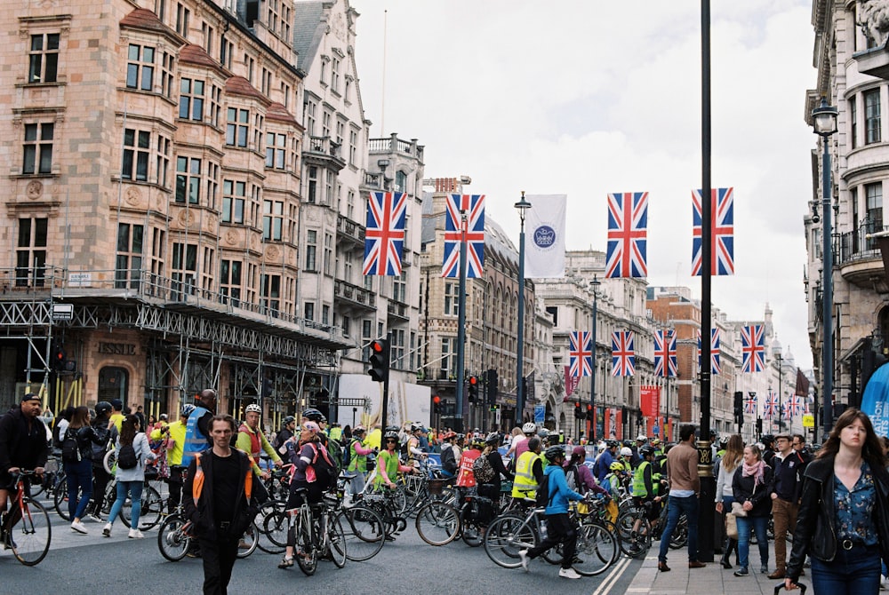 a crowd of people walking on a street with flags