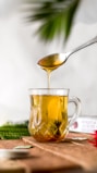 A warm cup of herbal Jamaican tea with honey dripping from a spoon.