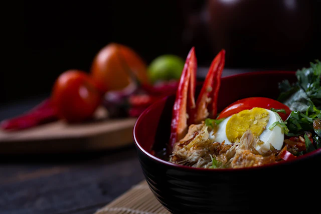A bowl of laksa with prawns, egg and chilli