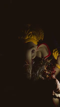 A serene photo of a softly lit Ganesha idol surrounded by marigold flowers.