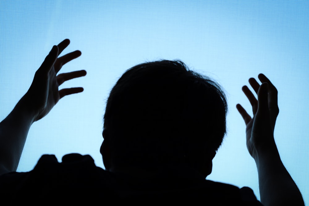 a silhouette of a man with his hands up