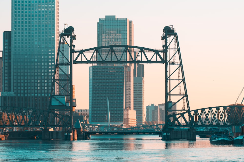 a bridge over water with tall buildings in the background