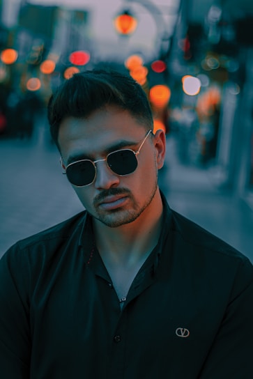 A vibrant photoshoot scene with a model wearing stylish glasses in an urban setting.