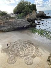 a stone walkway with a person walking on it next to a rocky beach