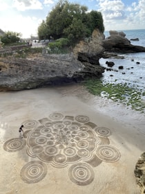 a stone walkway with a person walking on it next to a rocky beach