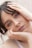 A close-up portrait of a person with light eyes and dark hair, resting their head in their hands. The expression is calm and introspective, with a subtle hint of emotion conveyed through the eyes.