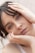 A close-up portrait of a person with light eyes and dark hair, resting their head in their hands. The expression is calm and introspective, with a subtle hint of emotion conveyed through the eyes.