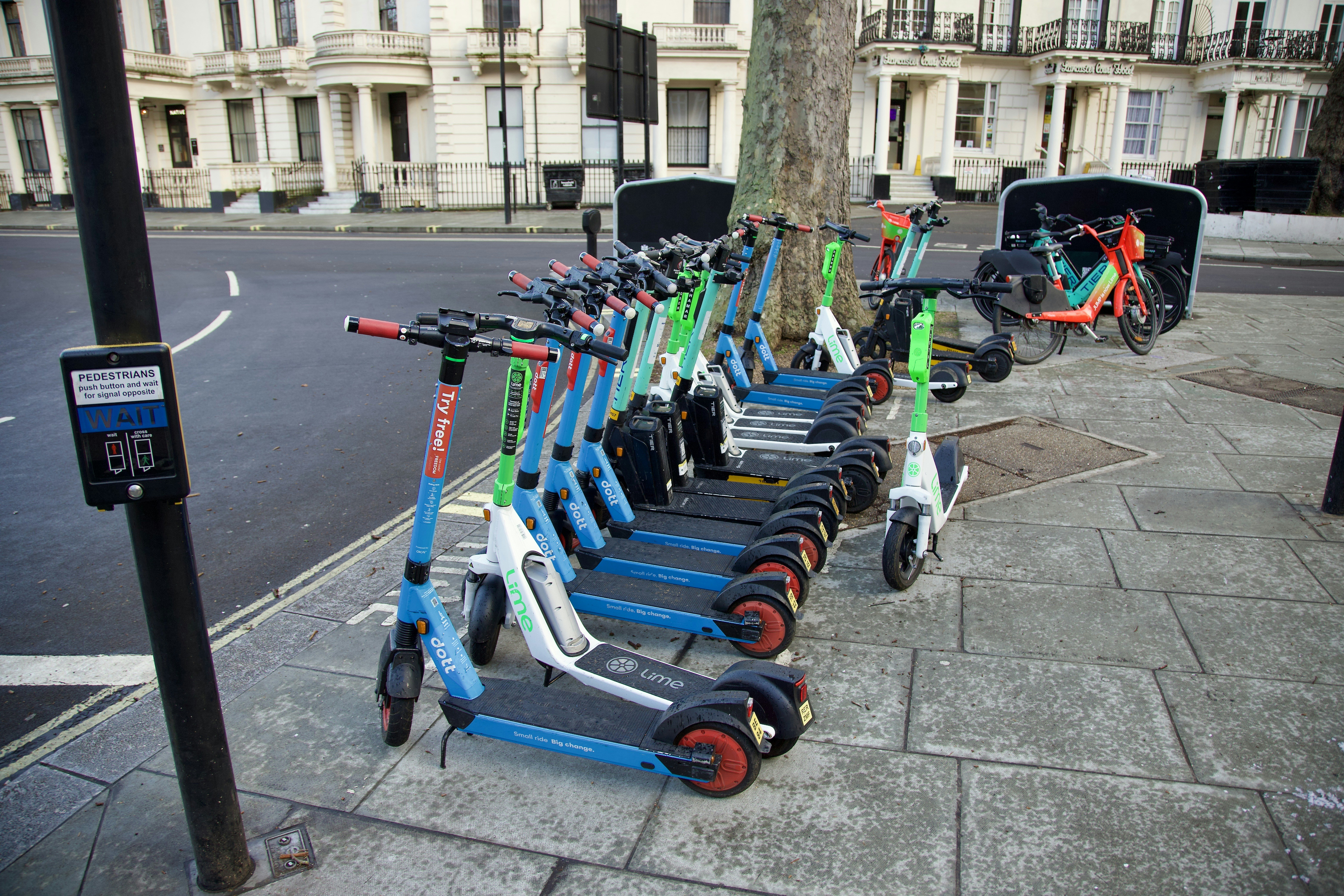 Row of compact electric cars parked along a city street, illustrating affordable EV options.