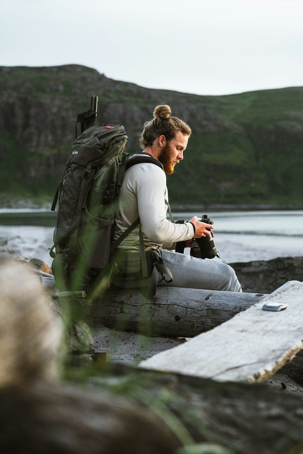 a person with a camera on a log by a body of water