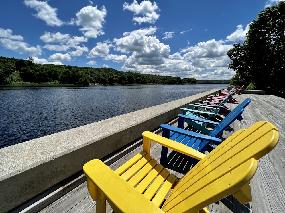 a row of colorful chairs on a dock by a body of water
