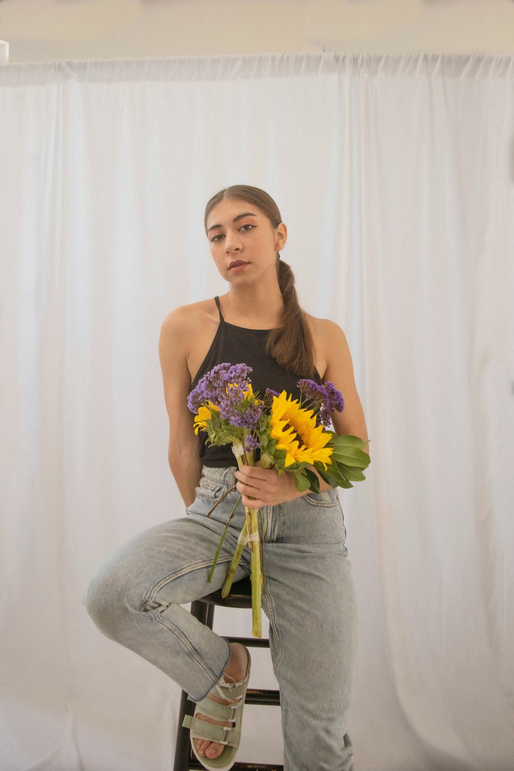 a person sitting on a stool holding flowers