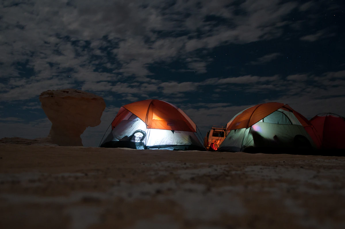 Lit tents at a desert camp under the stars
