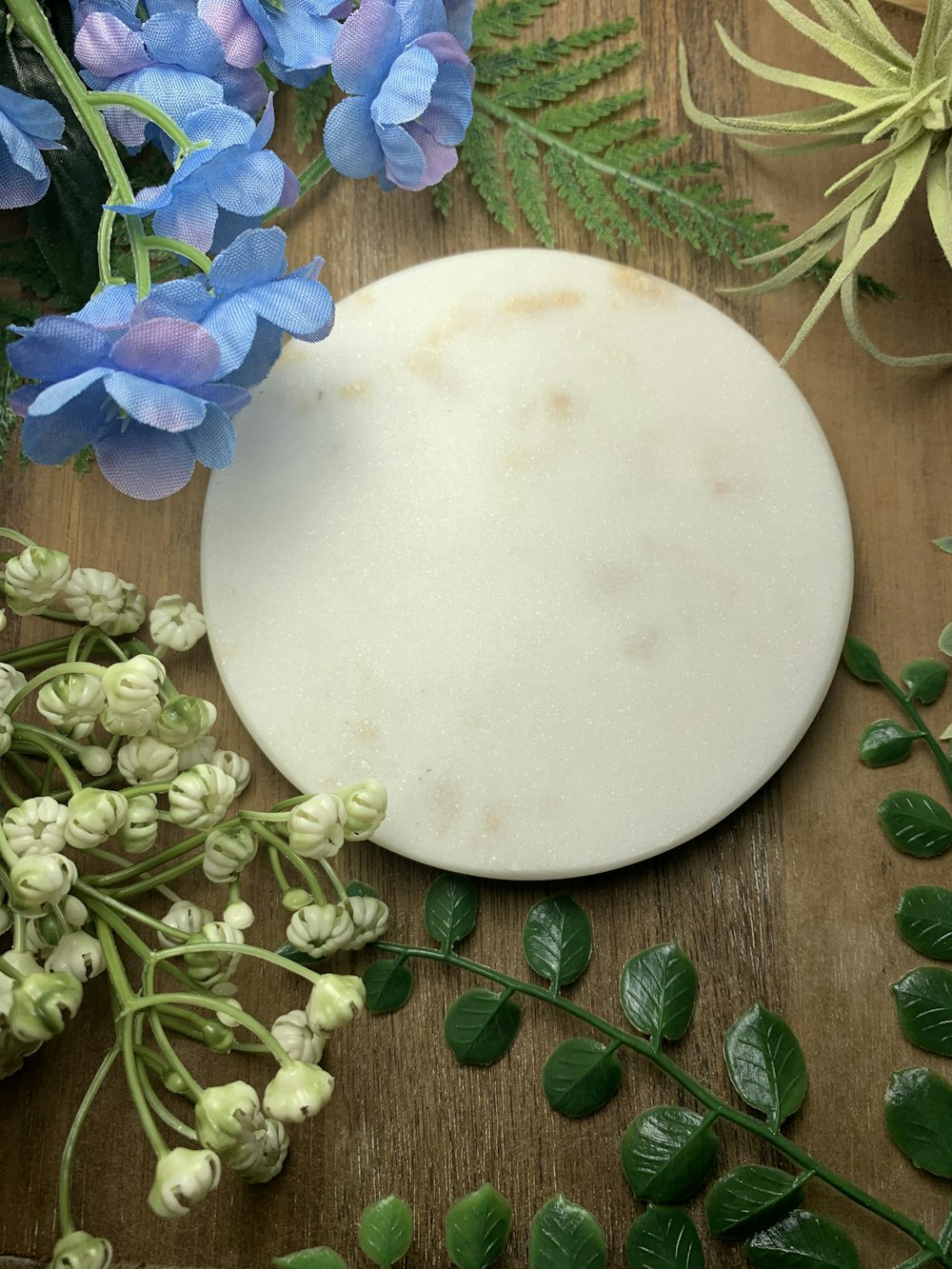 a white plate with a white substance on a wooden surface with flowers