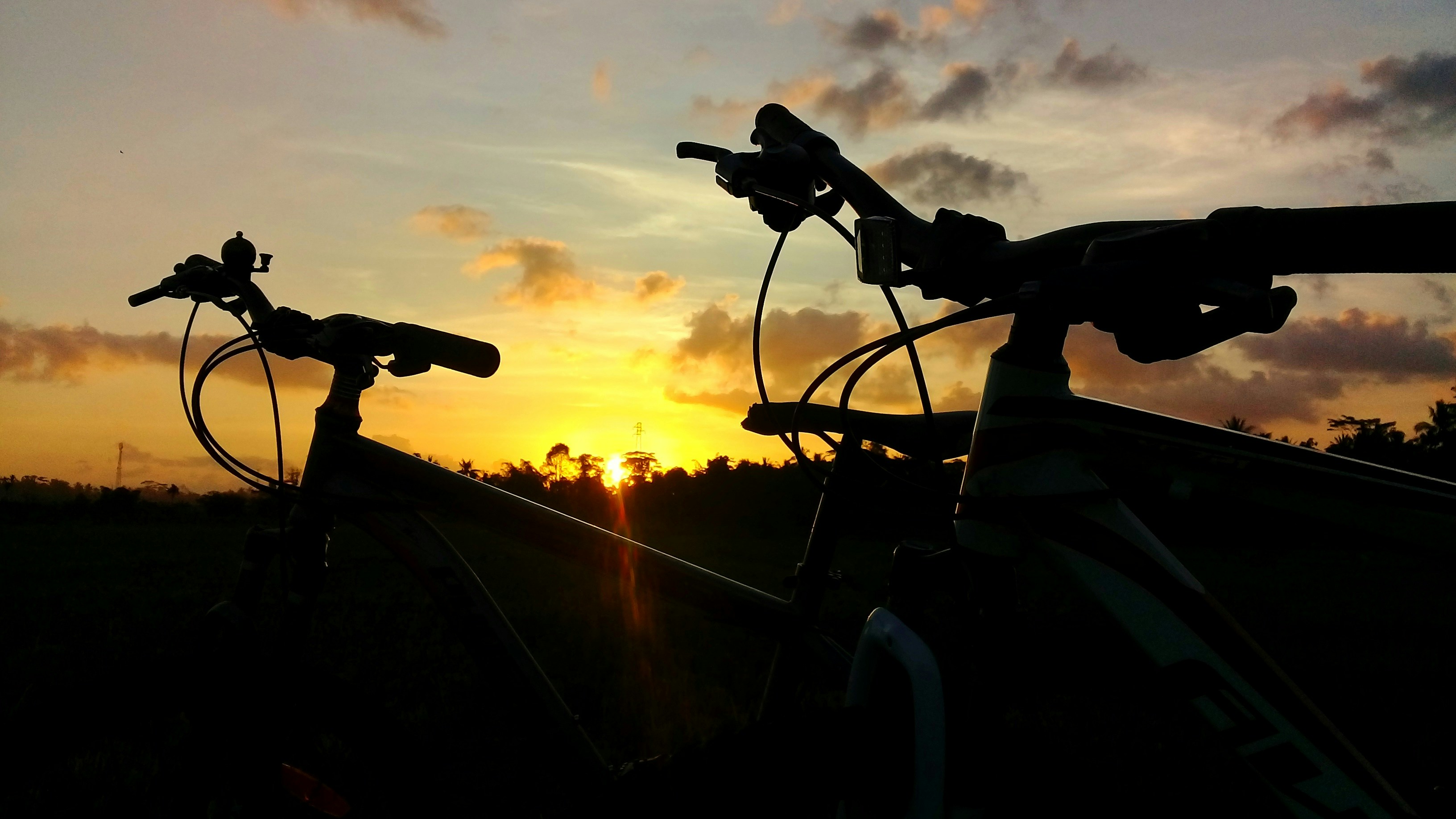 a bicycle on a road with a sunset in the background