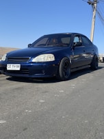 Side view of a car with tinted windows parked under a clear blue sky.