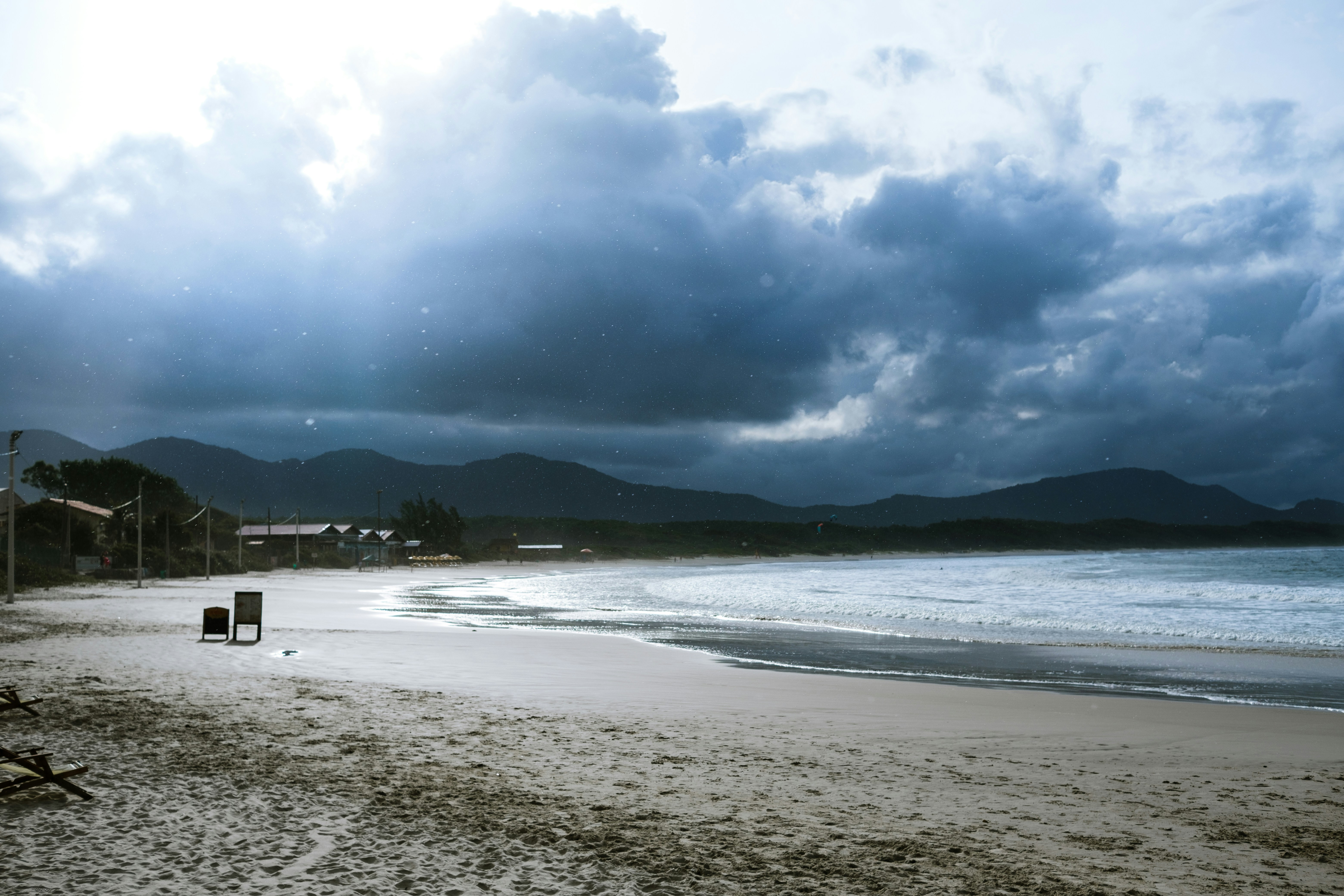 a beach with a body of water and mountains in the background