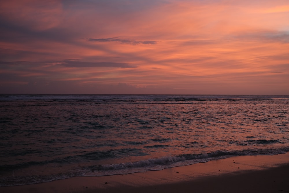 a beach with a pink and purple sky