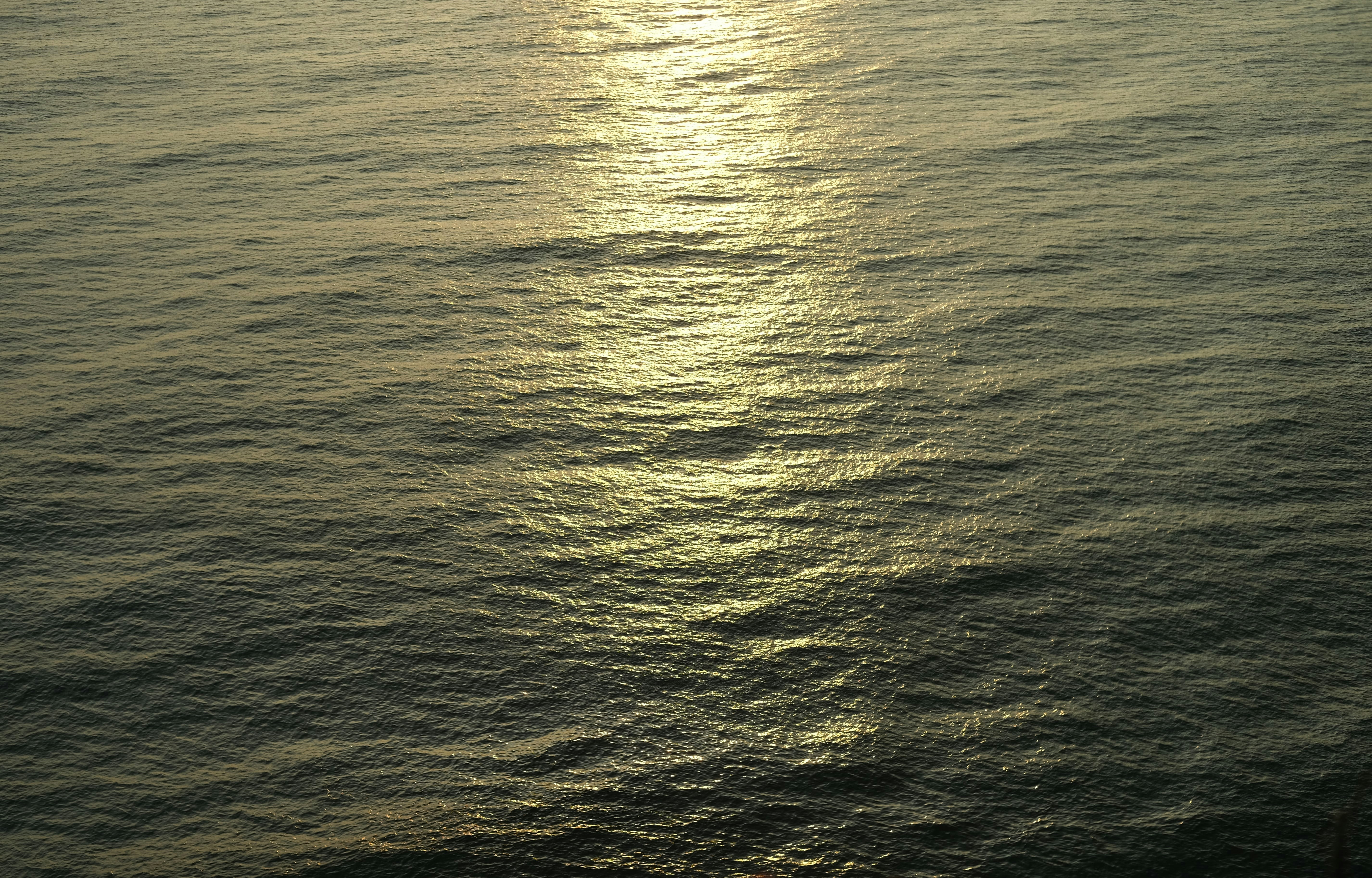 a body of water with a sun shining on it